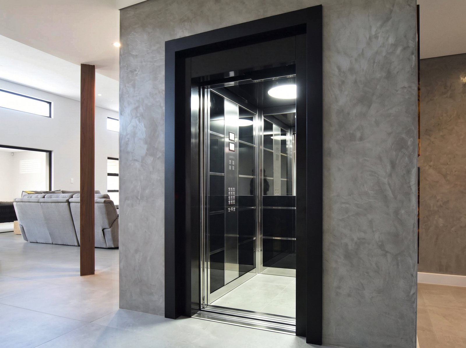 Cabina moderna para ascensor con acabados oscuros, espejos, iluminación y marco de acceso negro
