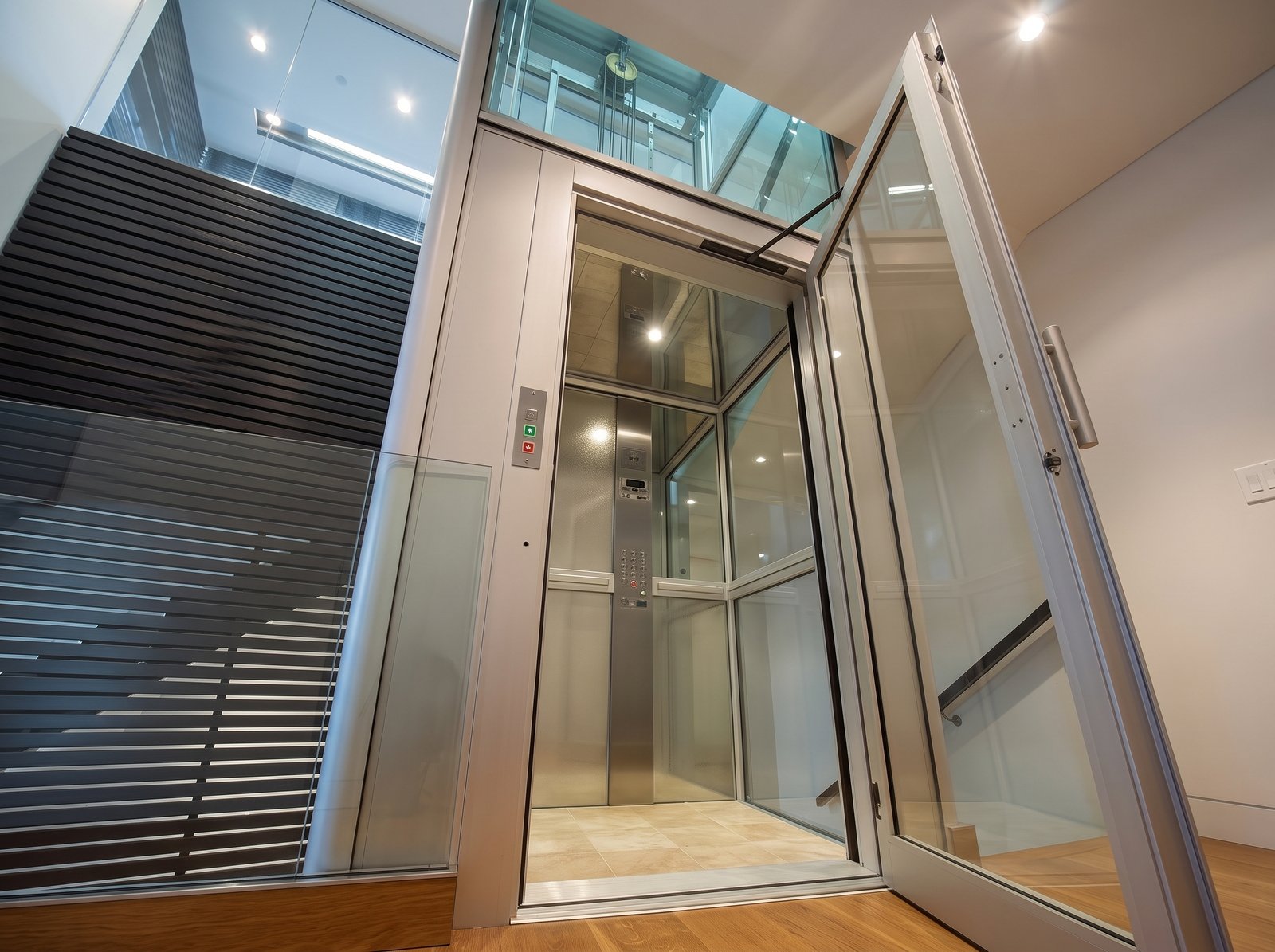 Cabina panorámica con cerramiento acristalado, acceso abierto y botonera exterior